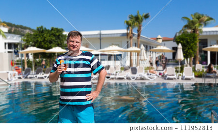 A male tourist from the USA on vacation in Turkey drinks a cocktail A male tourist from the USA on vacation in Turkey drinks a cocktail 111952813