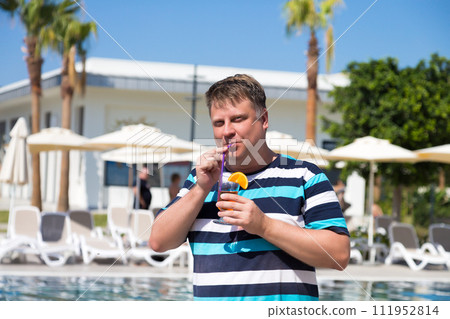 A male tourist from the USA on vacation in Turkey drinks a cocktail A male tourist from the USA on vacation in Turkey drinks a cocktail 111952814