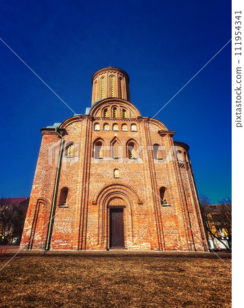 A red brick church with a cylindrical tower, arched doorways, and circular windows under a clear blue sky. Friday Church in Chernihiv. A red brick church with a cylindrical tower, arched doorways, and circular windows under a clear blue sky. Friday Church in Chernihiv. 111954341