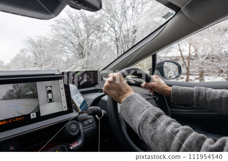 一輛汽車的駕駛座，一名男子在雪道上行駛 111954540