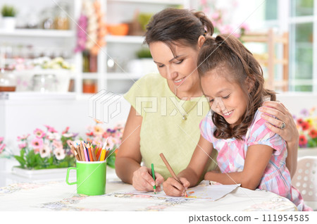 Cute little girl with her mother doing homework Cute little girl with her mother doing homework 111954585