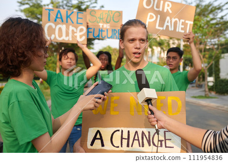 Eco activist answering questions of journalists when protesting with placard 111954836