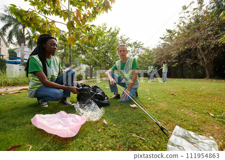 Volunteers cleaning park after big festival, collecting garbage into plastic bags 111954863