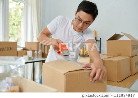 Volunteer packing boxes with products in office of charity organization 111954917