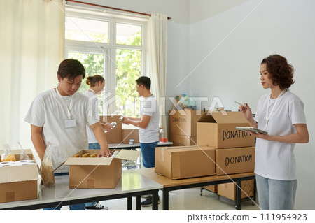 Volunteers checking boxes with donated products 111954923