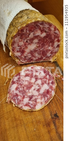 Artisanal salami slices on wooden cutting board. Vertical image 111954935