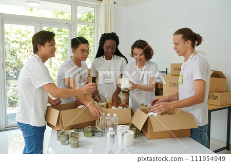 Diverse group of volunteers packing donated products in boxes for people in need Diverse group of volunteers packing donated products in boxes for people in need 111954949