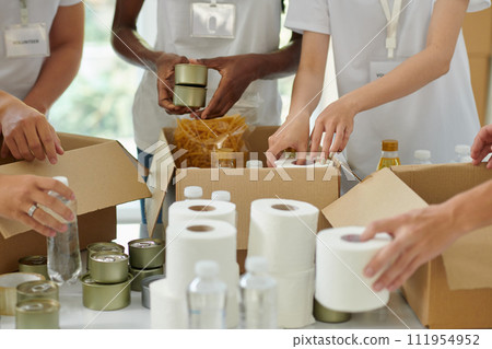 Volunteers packing donated goods in cardboard boxes Volunteers packing donated goods in cardboard boxes 111954952