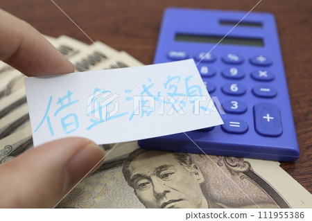 A paper with debt reduction written on it and a 10,000 yen bill A paper with debt reduction written on it and a 10,000 yen bill 111955386