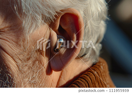 Ear of an elderly person with hearing aid 111955939