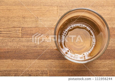 Nearly empty glass of beer on wooden table 111956244