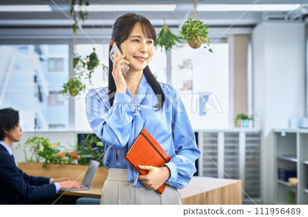 Business casual young woman calling on smartphone 111956489