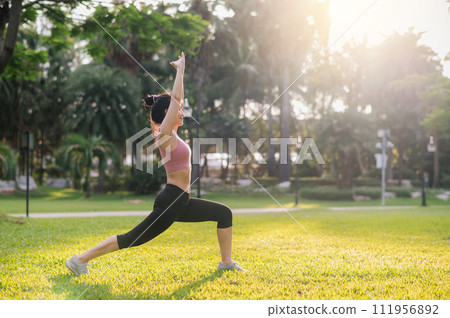 fit young 30s Asian woman in pink sportswear stretches muscles in park before refreshing run. the concept of wellness being and a healthy outdoor lifestyle with fitness runner girl in a public park. 111956892