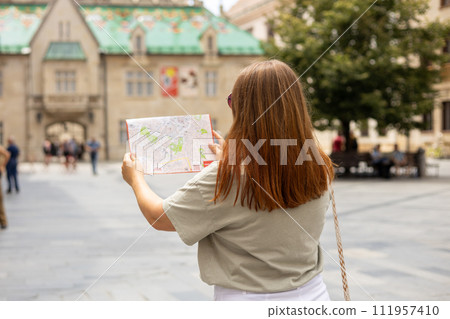 Happy tourist girl with map travels in Europe. Vacation concept by exploring interesting places to travel. Redhead Woman Searching locations at summer sunny day Happy tourist girl with map travels in Europe. Vacation concept by exploring interesting places to travel. Redhead Woman Searching locations at summer sunny day 111957410