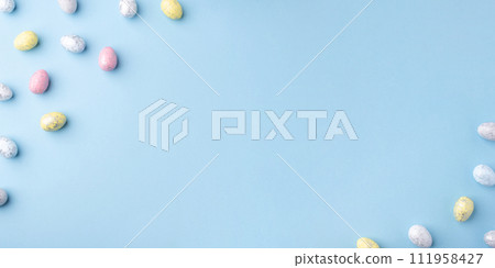 Festive Easter background. Multicoloured Easter eggs on a blue table. Banner with a place for text. Top view. 111958427
