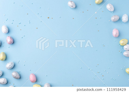 Festive Easter background. Multicoloured Easter eggs on a blue table. Banner with a place for text. Top view. Festive Easter background. Multicoloured Easter eggs on a blue table. Banner with a place for text. Top view. 111958429