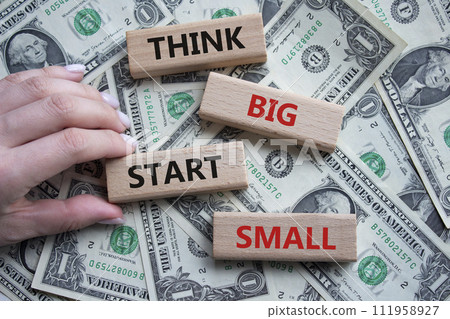 Think big start small symbol. Concept words Think big start small on wooden blocks. Beautiful dollar background. Businessman hand. Business and Think big start small concept. Copy space 111958927