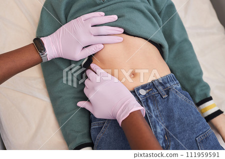 Close up of unrecognizable pediatrician palpating stomach of child lying on cot in medical clinic during physical examination Close up of unrecognizable pediatrician palpating stomach of child lying on cot in medical clinic during physical examination 111959591