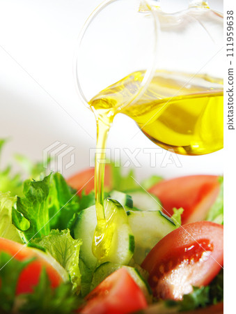 Drizzle olive oil on lettuce and tomato salad 111959638