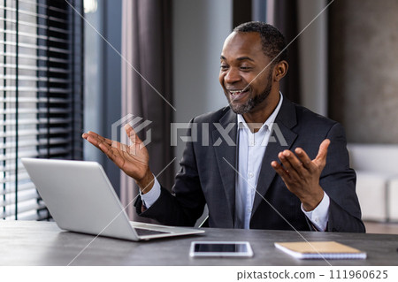 Successful mature boss in business suit inside office with laptop, talking remotely using video call, man smiling gesturing satisfied, businessman investor at work. Successful mature boss in business suit inside office with laptop, talking remotely using video call, man smiling gesturing satisfied, businessman investor at work. 111960625