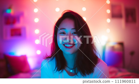 Korean girl portrait, asian girl blogger records video in front of the screen in the room, in the background there is a multi-colored LED backlight 111960811
