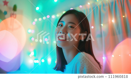 Korean girl portrait, asian girl blogger sits sideways to the camera in front of the screen in the room, in the background there is a multi-colored LED backlight Korean girl portrait, asian girl blogger sits sideways to the camera in front of the screen in the room, in the background there is a multi-colored LED backlight 111960818