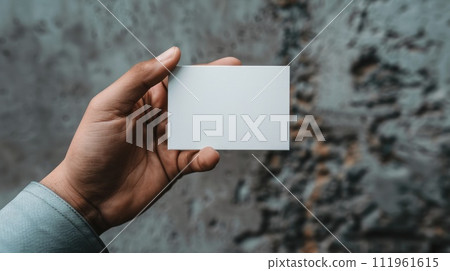 A person holding a white business card against a concrete wall backdrop A person holding a white business card against a concrete wall backdrop 111961615