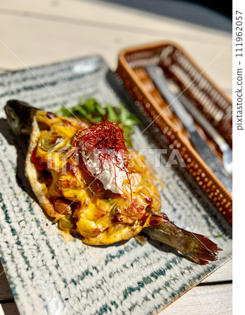 Appetizer with smoked fish and cheese on a table in a restaurant. Fried fish with cheese on a plate in a restaurant. Selective focus. Appetizer with smoked fish and cheese on a table in a restaurant. Fried fish with cheese on a plate in a restaurant. Selective focus. 111962057
