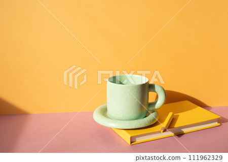 Notebook and colored pencil, coffee cup on pink desk. orange wall background. workspace Notebook and colored pencil, coffee cup on pink desk. orange wall background. workspace 111962329