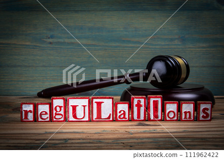 REGULATIONS. Red alphabet letters and judge's gavel on wooden background. Laws and Justice concept REGULATIONS. Red alphabet letters and judge's gavel on wooden background. Laws and Justice concept 111962422