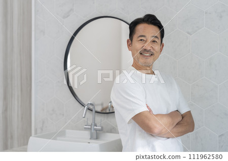 A man in his 50s wearing a white T-shirt smiling at the camera 111962580