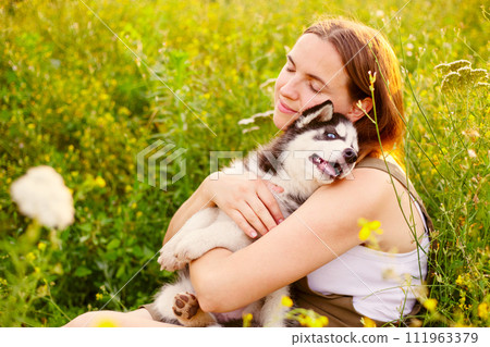 Woman playing with cute little husky puppy dog outdoors. Pet and owner love 111963379