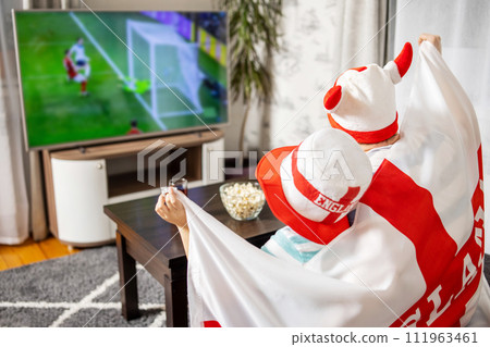 Father and son with England flag watching soccer game on TV 111963461