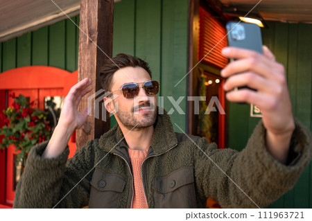Man in trendy jacket and sunglasses taking selfie Man in trendy jacket and sunglasses taking selfie 111963721