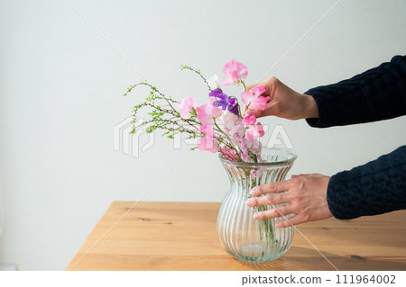 Hands of a woman arranging flowers Hands of a woman arranging flowers 111964002