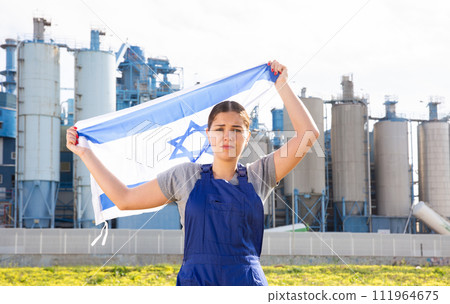 Sad young woman near factory with Israel flag 111964675