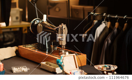 Fashion atelier sewing machine and tools on workshop table, luxury tailoring design and industrial materials. Workstation with fabric and pins for clothes manufacturing process. Close up. Fashion atelier sewing machine and tools on workshop table, luxury tailoring design and industrial materials. Workstation with fabric and pins for clothes manufacturing process. Close up. 111964676