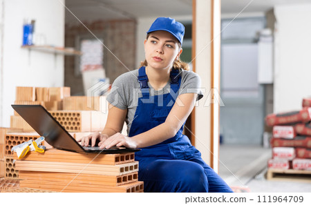 Woman construction worker using laptop in apartment 111964709