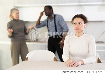 Adult sad woman sitting at table during family quarrel 111964774