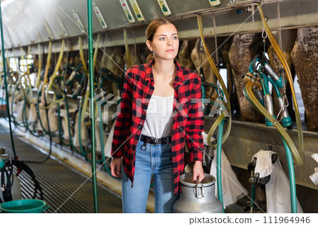 Young woman farmer holding milk can at the cow farm 111964946