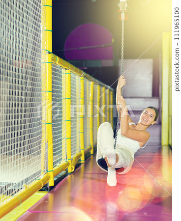 Cheerful girl swinging on indoor zip line at play center 111965100