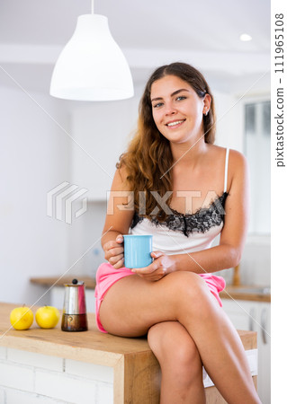 Portrait of dreaming girl with cup of coffee in her hands in modern kitchen Portrait of dreaming girl with cup of coffee in her hands in modern kitchen 111965108