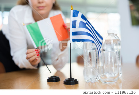 Unrecognizable girl sets midget flags of Greece and Italy before international negotiations Unrecognizable girl sets midget flags of Greece and Italy before international negotiations 111965126