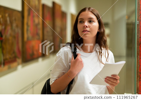 Portrait of a girl standing in a museum next to an exhibit, located in a glass cabinet Portrait of a girl standing in a museum next to an exhibit, located in a glass cabinet 111965267