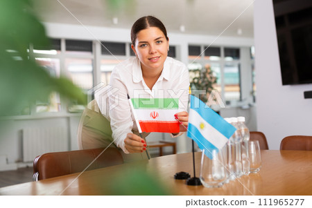 Employee of delegation prepares negotiating table - sets up flag of Argentina and Iran Employee of delegation prepares negotiating table - sets up flag of Argentina and Iran 111965277