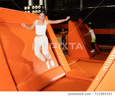 Excited girl pushing off from angled surface in trampoline park Excited girl pushing off from angled surface in trampoline park 111965281