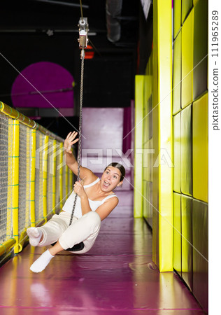 Cheerful girl swinging on indoor zip line at play center 111965289