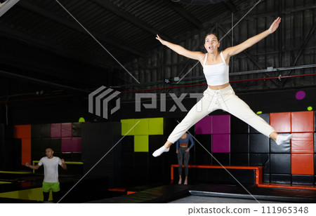 Excited young girl jumping at indoor trampoline center 111965348