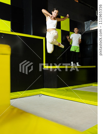 Happy girl bouncing on trampoline in indoor amusement park 111965356