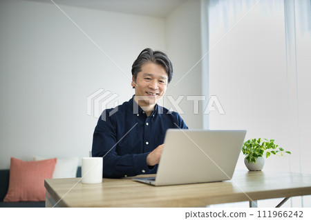 Middle-aged man doing telework in the living room Middle-aged man doing telework in the living room 111966242